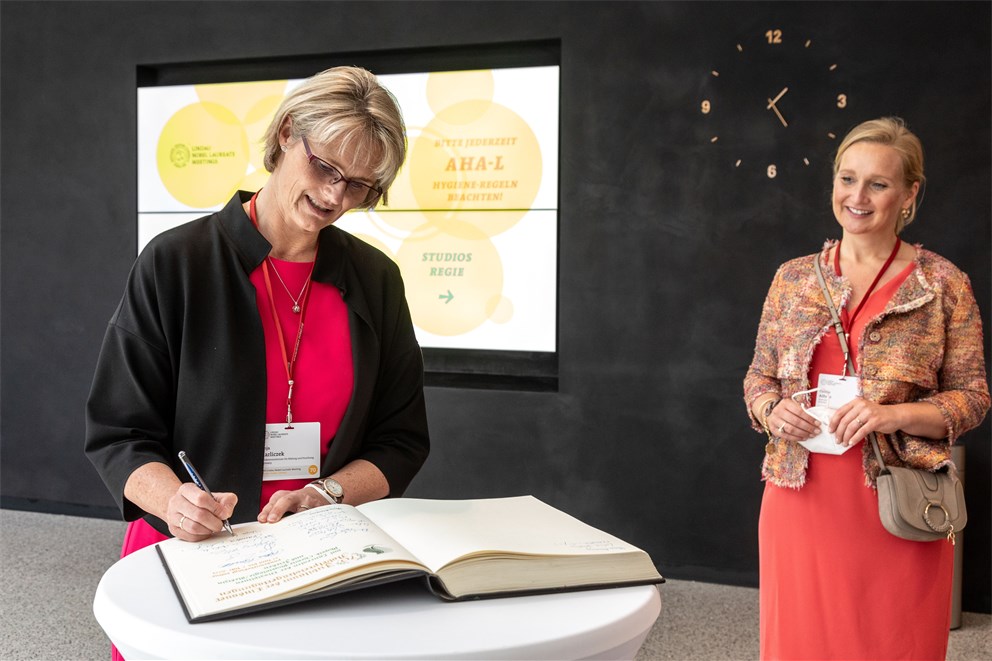 German Federal Minister for Education and Research, Anja Karliczek, signs the golden book of Lindau. Mayor of Lindau, Claudia Alfons, is standing next to her.